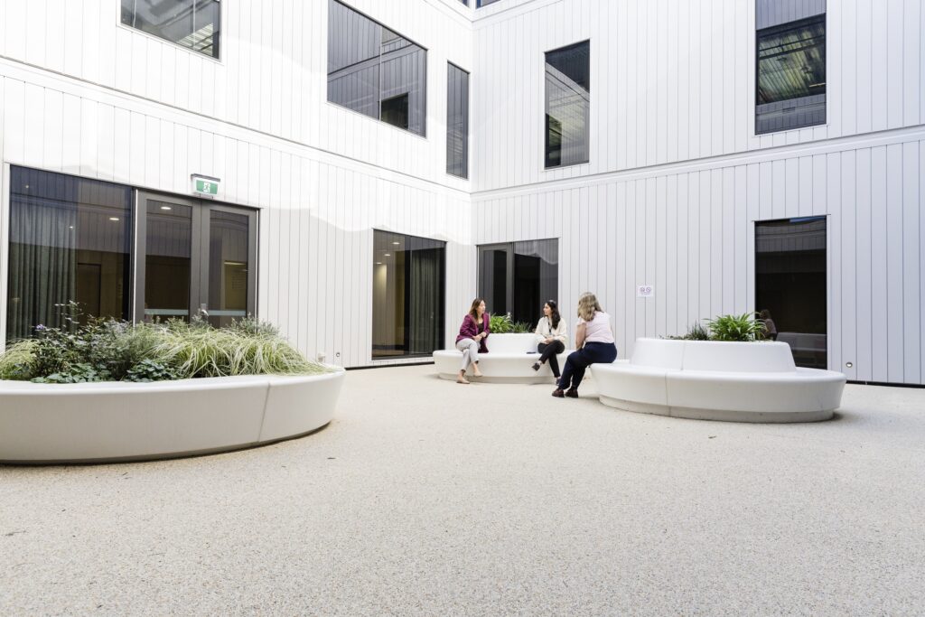Patients are seen enjoying the courtyard of the mental health women's inpatient unit. It is an outdoor, 
open space within the unit that has seats and plants.